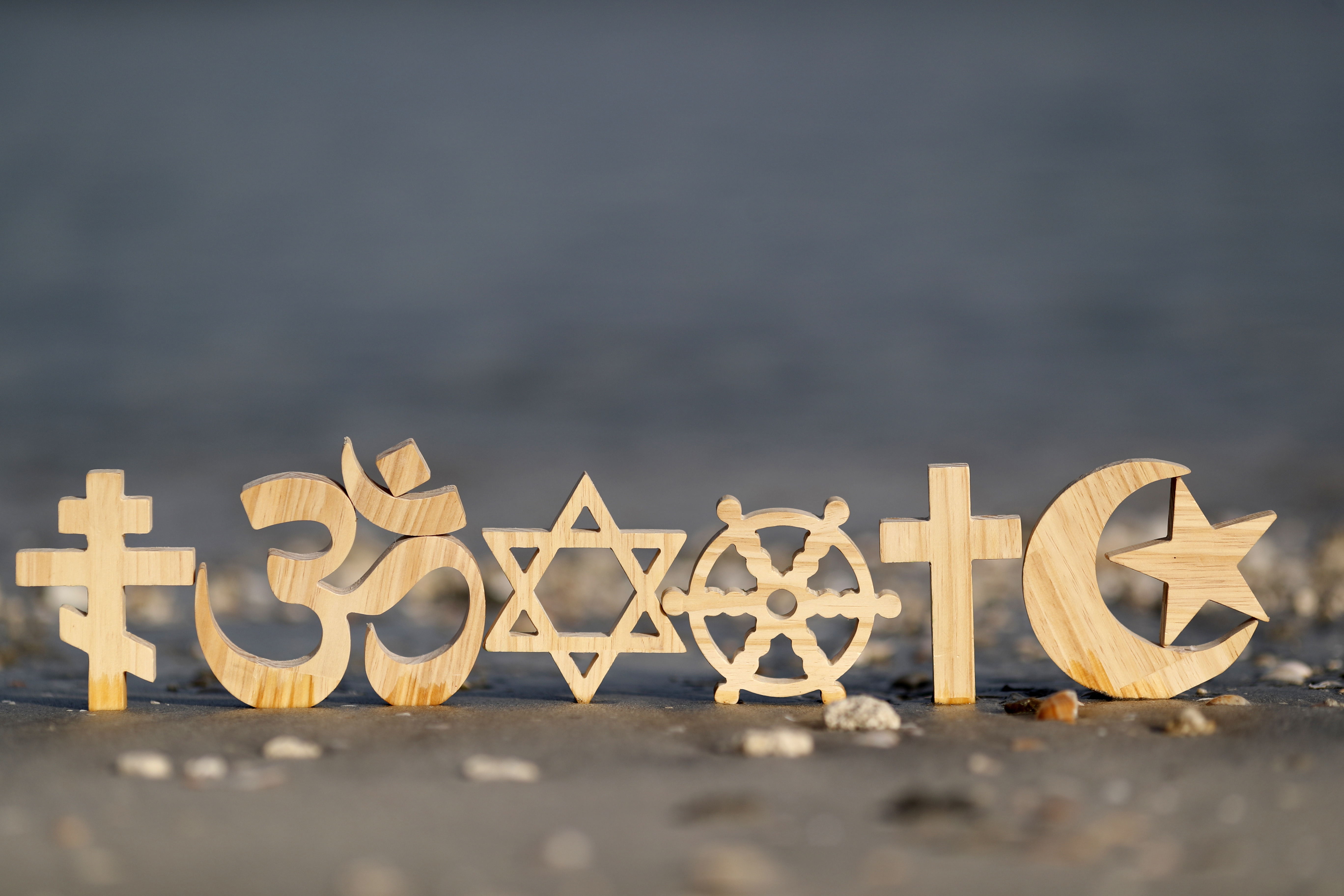 Diverse religiöse Symbole am Strand im Sand