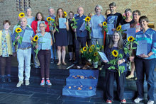 Gruppenbild von mehreren Menschen mit einer Sonnenblume