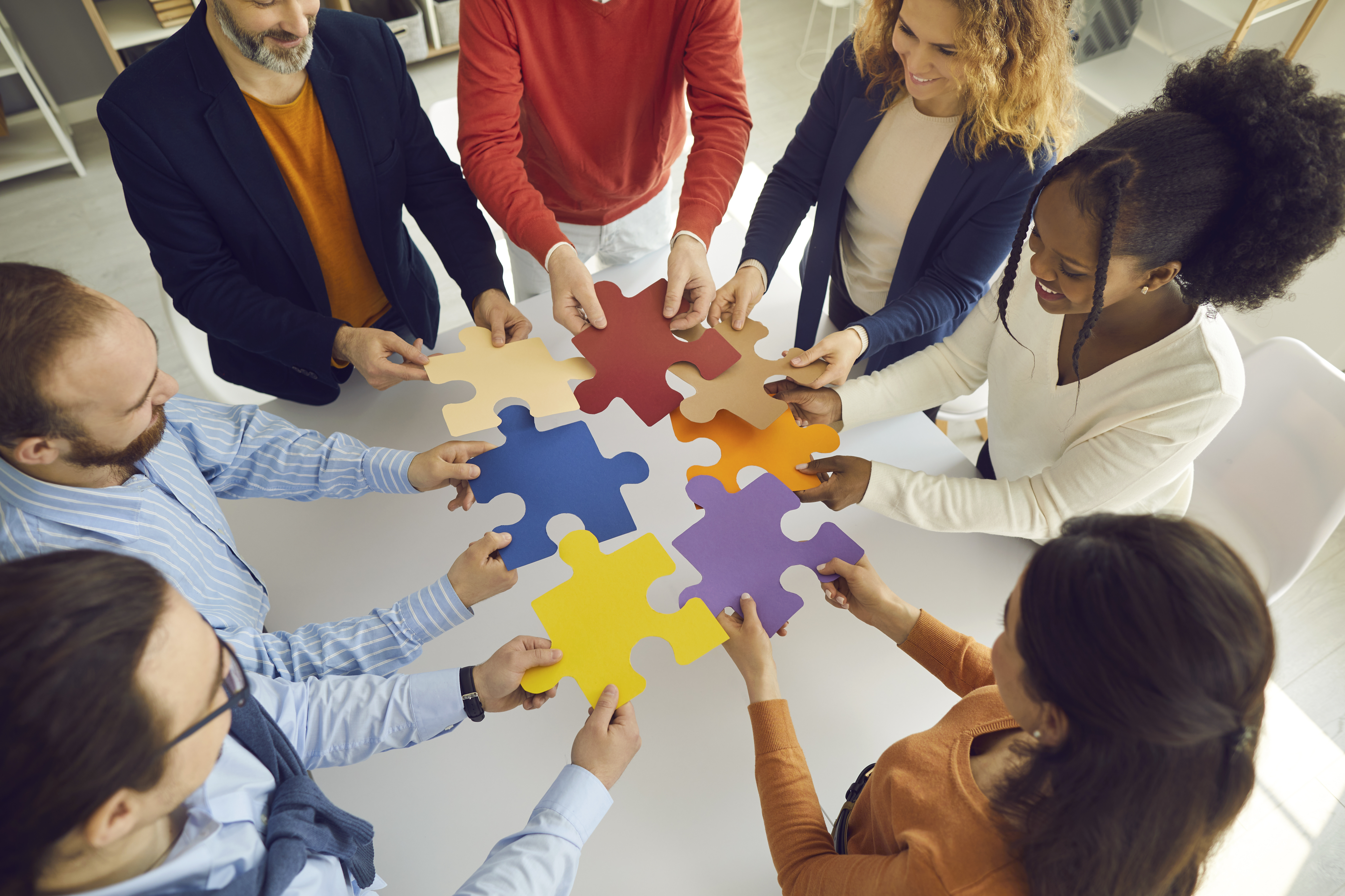 Menschen halten bunte Puzzleteile aneinander